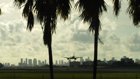 airplane landing over a city skyline with palm trees