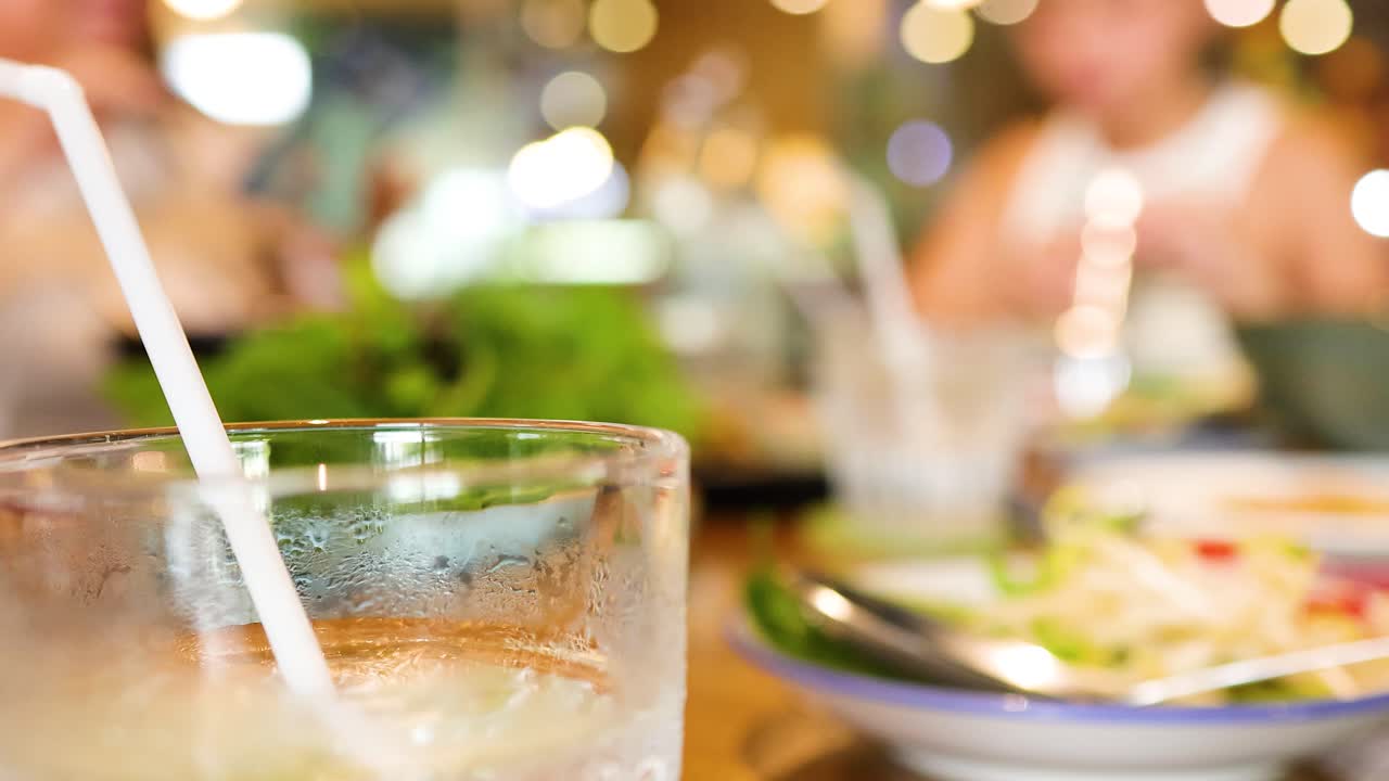 A vibrant Vietnamese restaurant scene with iced drinks and dishes, capturing a lively dining atmosphere with blurred background