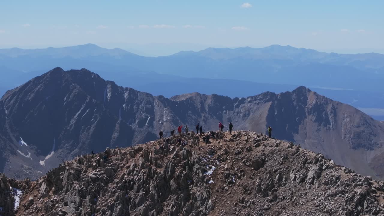 Hikers on a Rocky Mountain Summit with Distant Peaks