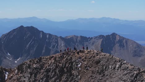 hikers on a rocky mountain summit with distant peaks