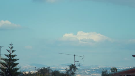 Time-lapse-fast-motion-shot-of-a-surfing-clouds-in-the-blue-skies,-green-tree,-hill-in-the-background,-4K-Video