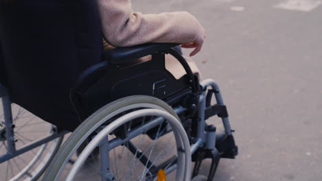 Camera-Focuses-On-Wheels-Of-A-Wheelchair-Spinning-On-A-Walk-In-The-Street-1