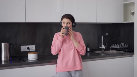 Woman-Listening-To-Music-With-Headphones-At-Home-With-Cup-Of-Coffee