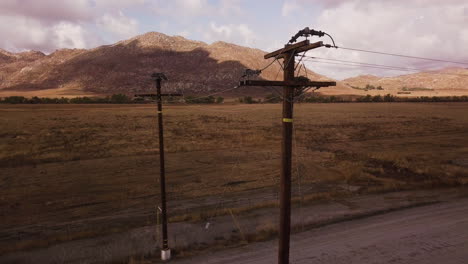 power lines over the dusty road in the desert, parched land and the mountains in the background