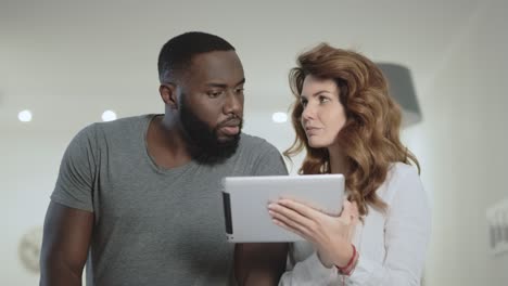 Young couple choosing photo at living room together.