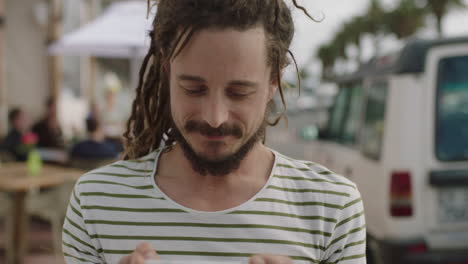 portrait of young friendly man on vacation taking photo using smartphone