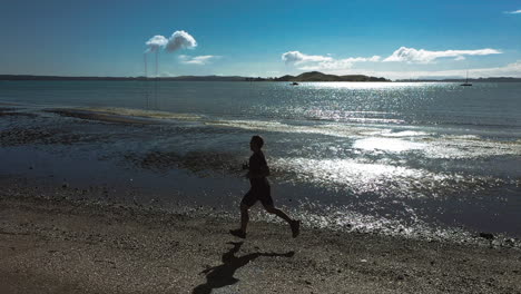Male fast runner running along shingle beach formed of pebbles, aerial shot