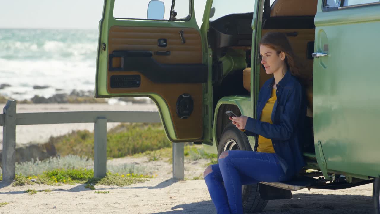 una hermosa mujer joven enviando mensajes de texto por teléfono móvil en una furgoneta 4k