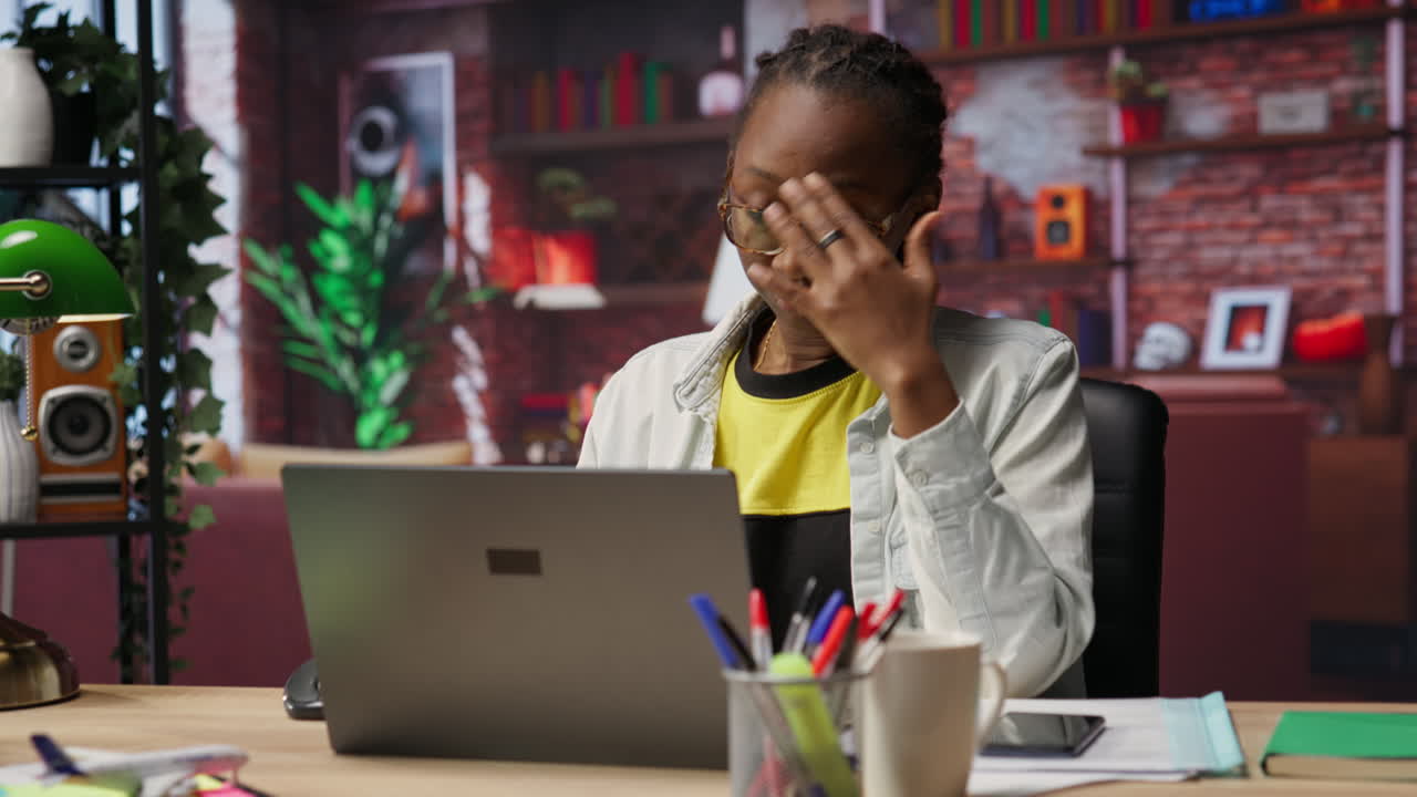 Tired woman in living room office sighing, overworked by tasks