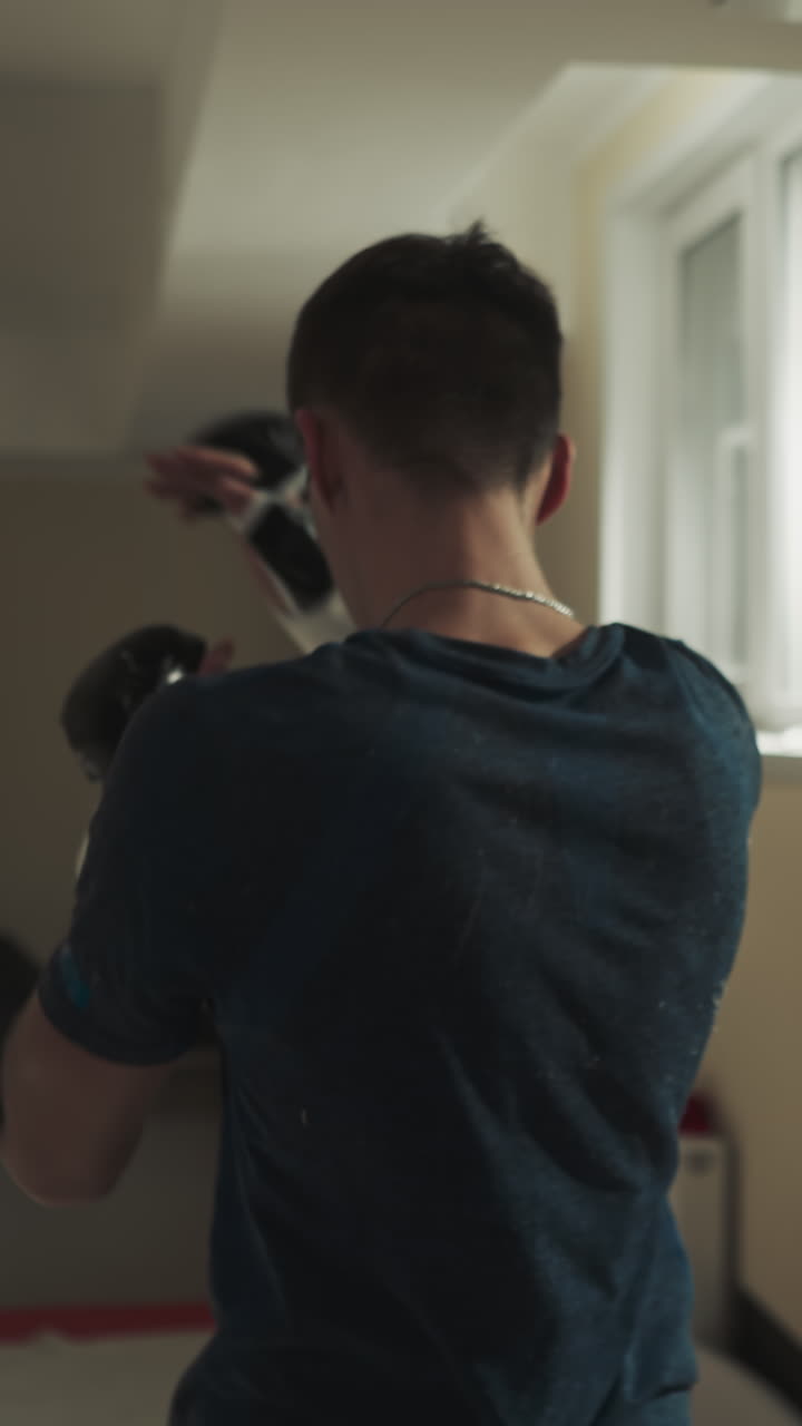 권투 장갑을 입은 남성 선수는 지하실에서 트레이너의 감독 하에 전문적인 치를 개발합니다.