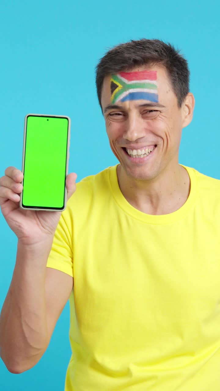 South African supporter looking at his mobile smiling and showing it