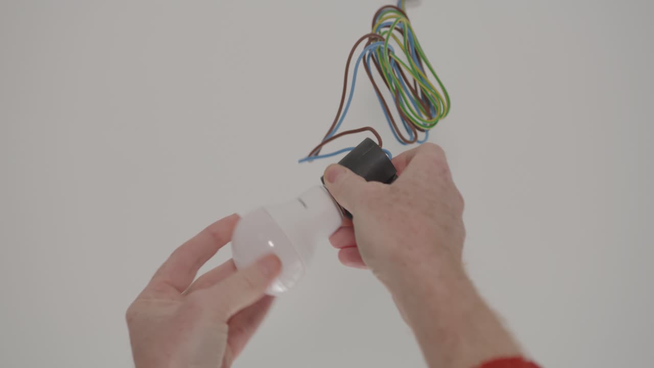 Hands inserting led-light bulb into socket of ceiling