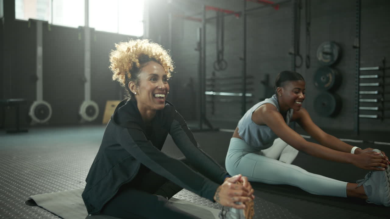 Two women stretching in a gym