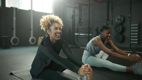 two women stretching in a gym
