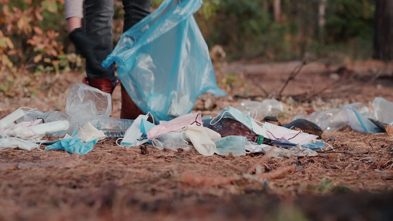 una mujer recoge máscaras médicas y basura plástica en un bosque 1
