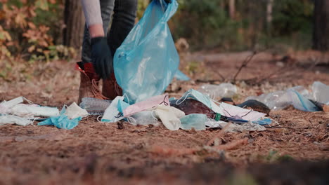 una mujer recoge máscaras médicas y basura plástica en un bosque 1