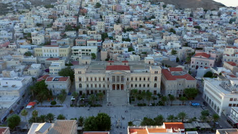 aerial: slow panoramic drone shot of miaouli square and city hall building in ermoupoli of syros island, greece during sunset