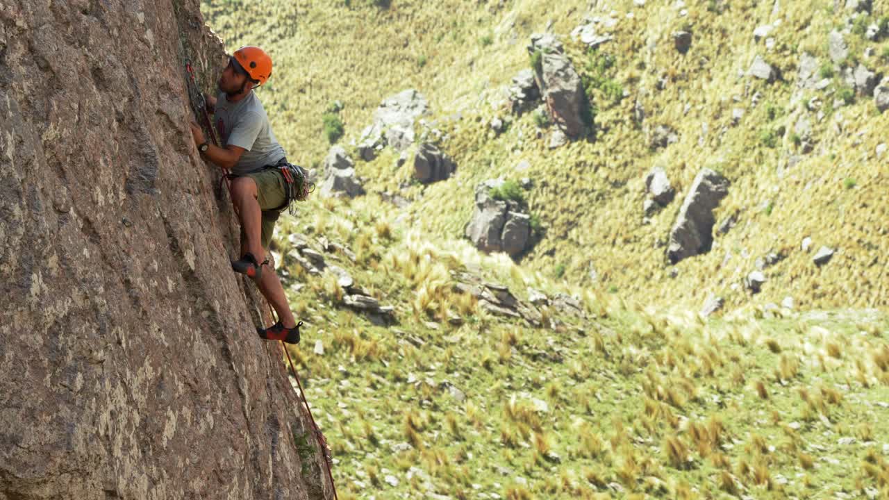 A middle aged man challenging gravity while leading a rock climb on a steep wall
