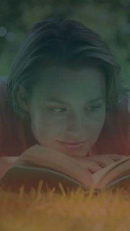 animation of lights over caucasian woman lying on lawn and relaxing with book