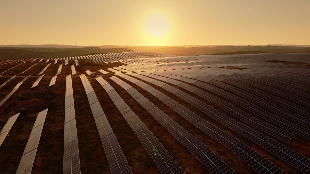 Luftfoto af stor solcellepark ved solnedgang