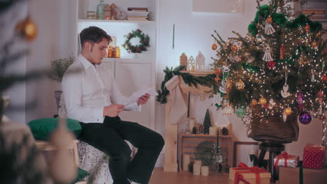 man reading letter at decorated home during christmas