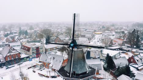 aerial view of dutch windmill and snow capped village on cold winter day, drone shot