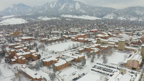 cars driving on snowy road over university of colorado boulder campus during misty winter day in colorado - aerial drone backwards flight