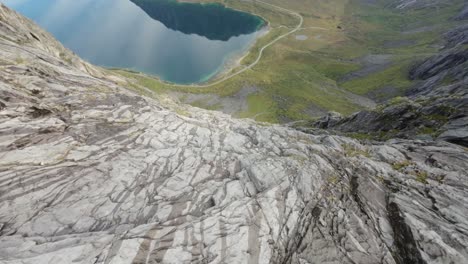 Diving-down-the-steep-mountainsides-in-Grøtfjord,-Norway,-revealing-a-crystal-clear-fjord