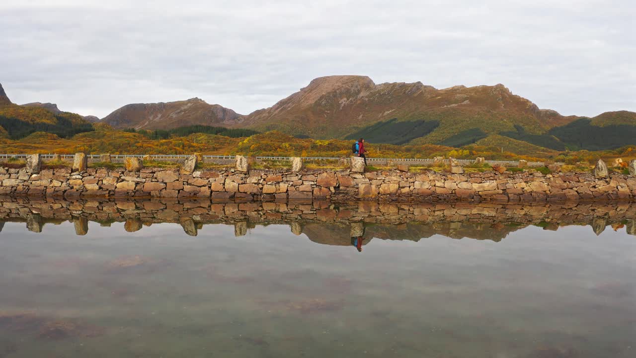 Tranquil scene of two people walking along a stone pathway in Vestarelen, Norway, with mountains
