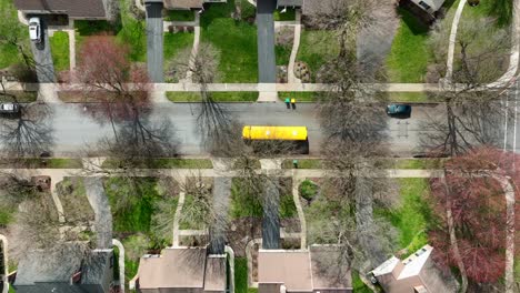 Aerial-top-down-tracking-of-school-bus-driving-through-American-suburb