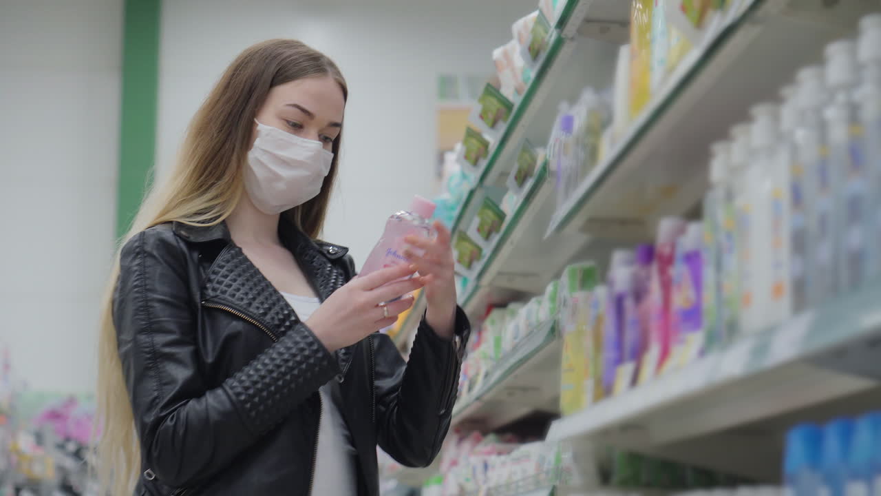마스크를 착용 한 식료품 가게에서 미용 제품을 구매하는 여성