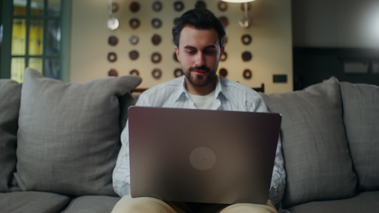 hombre trabajando en una computadora portátil en un sofá en casa