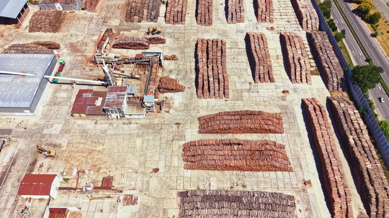 Wood storage area with logs stacked in rows during the day in a lumber yard