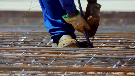 tying rebar with wire in a grid before pouring a concrete foundation