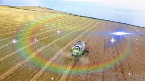 combine harvester moving across aerial farmland, kicking dust plume under rainbow lens flares
