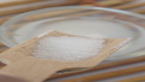 primer plano de una cuchara de madera con cristales de sal sobre un cuenco de sal