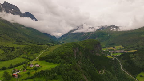 Breathtaking-aerial-panorama-of-verdant-valley,-low-clouds