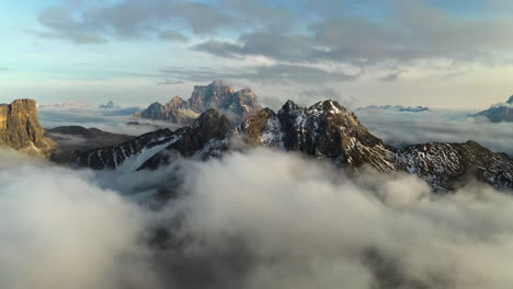 snowy mountain peaks surrounded by low hanging clouds in tyrol, italy - aerial view