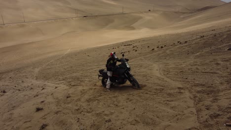 motocicleta atrapada en la arena en la cima de una colina empinada o duna en el desierto