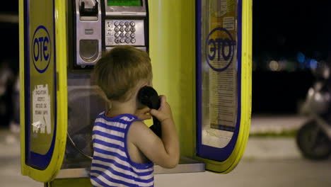 young boy talking to the phone in a booth