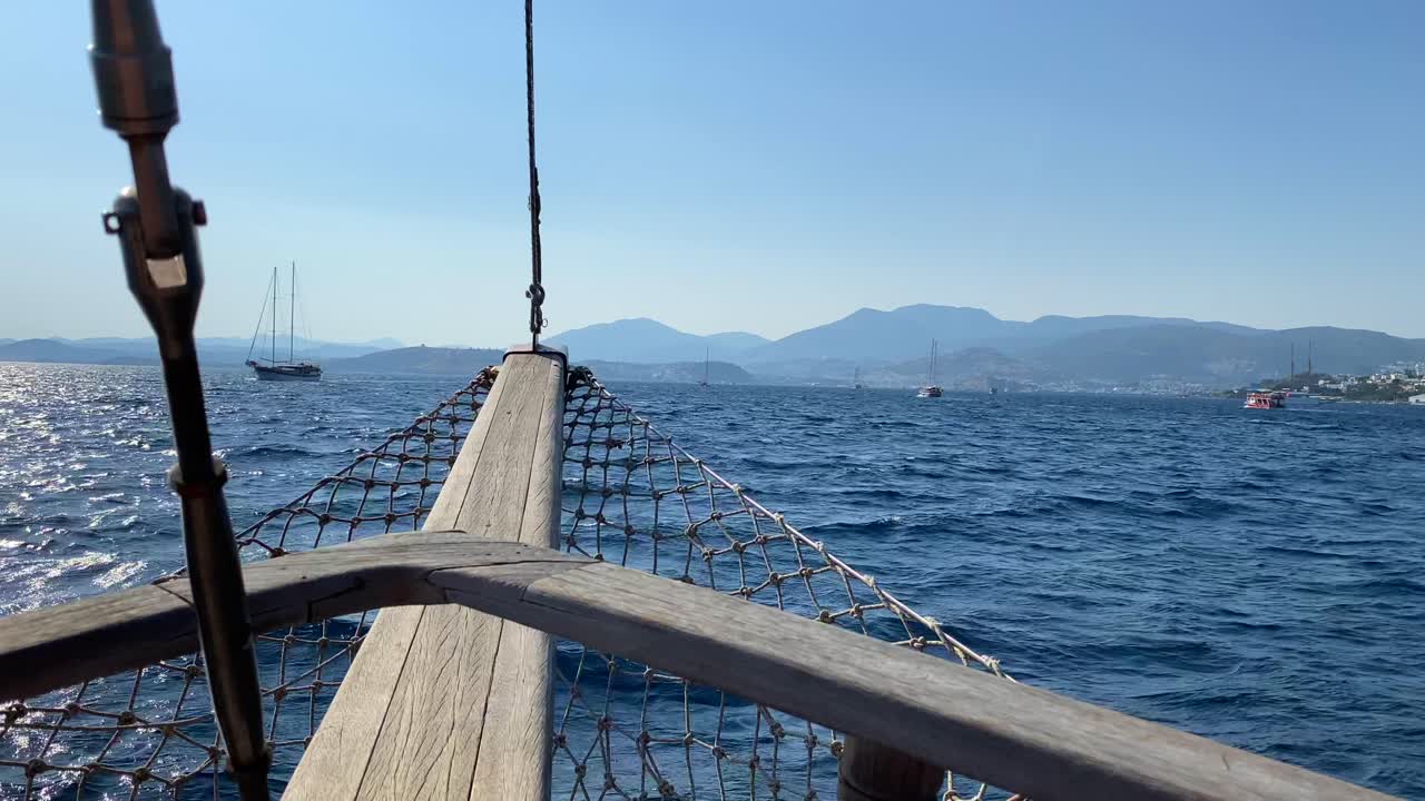 Wooden bow view on a big sailing boat in Bodrum Turkey, fun summer vacation, the front of a moving boat, luxury holiday destination, sunny sea day with blue sky, 4K shot