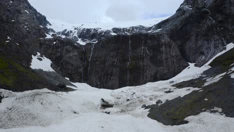 Slow-motion-flight-ascending-over-a-glacial-valley-up-to-mountain-cliff-in-Fiordland,-New-Zealand,-South-Island