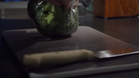 close-up: plastic wrap removed from broccoli crown on cutting board