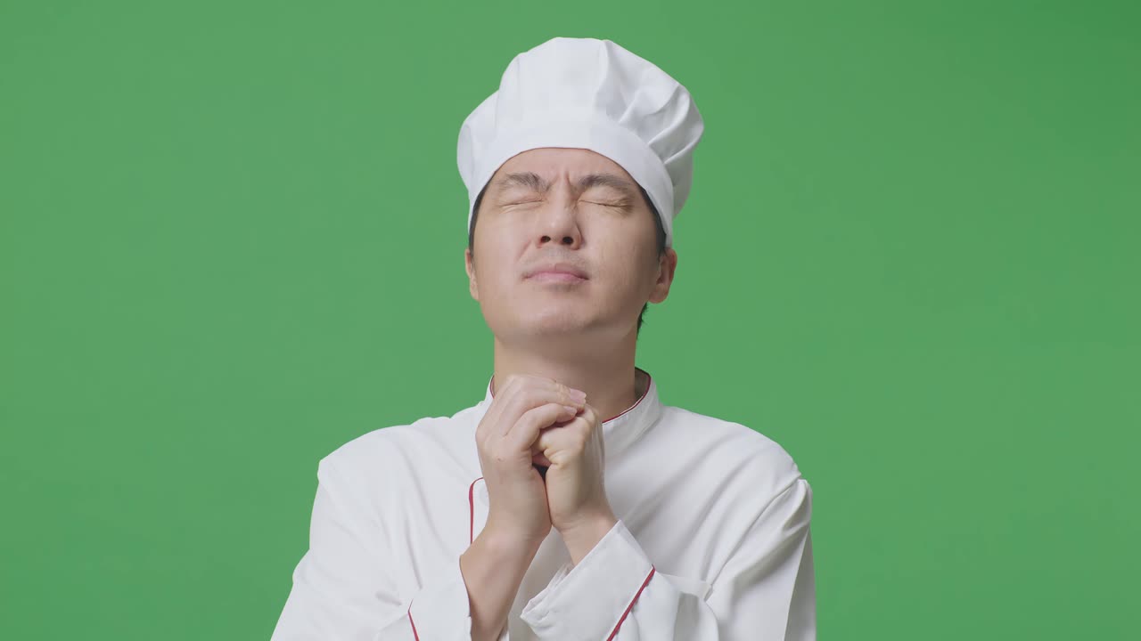 Close Up Of Asian Man Chef Praying For Something While Standing In The Green Screen Background Studio