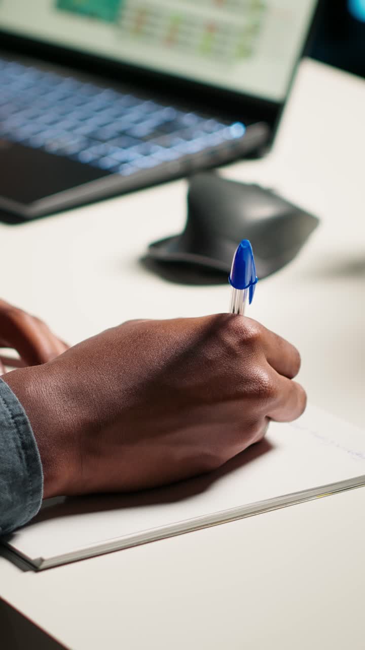 Primo piano di una persona che scrive su un quaderno a una scrivania