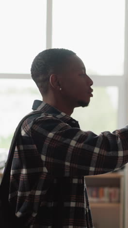 man seeks book on shelf in library. african american student chooses literature for homework making in university information center. guy in bookstore