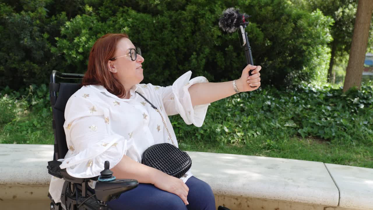 Woman in wheelchair vlogging in the park