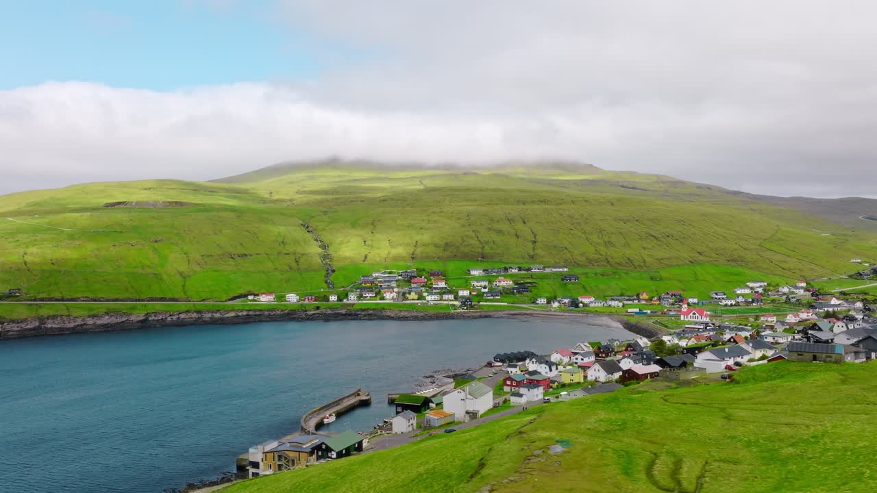 A picturesque coastal village in the Faroe Islands with lush green hills and calm waters