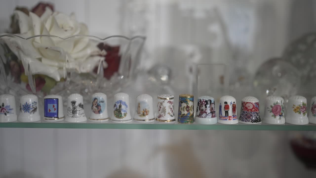 Porcelain thimbles arranged on glass shelf in soft indoor light