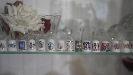 porcelain thimbles arranged on glass shelf in soft indoor light